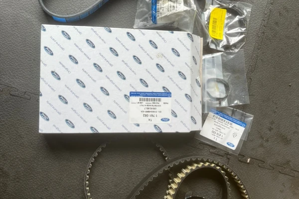 Genuine Ford OEM wet belt replacement kit including drive belt, tensioner, oil seals, and timing components laid out on a workshop surface, used for Ford EcoBoost engine repairs at MB MOTORS Rugeley.